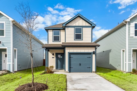A house with a blue garage door is in front of other similar houses.