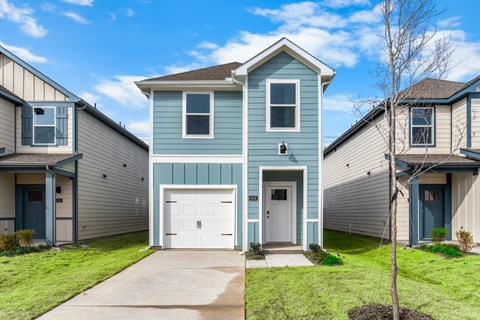 A blue house with a white garage door is in front of other houses.