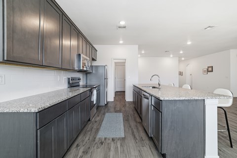 A kitchen with dark wood cabinets and a granite countertop.