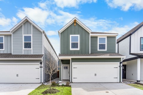A house with a grey and green exterior and two garages.