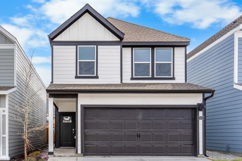 A two-story house with a garage door that is open.