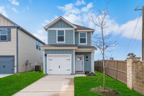 A two-story house with a garage and a tree in front.