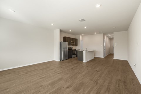 A spacious room with wooden flooring and white walls.