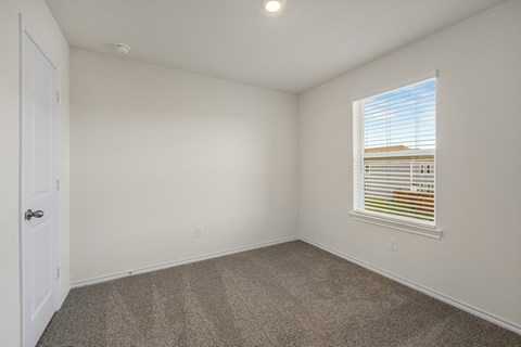 A room with a carpeted floor and a window with blinds.