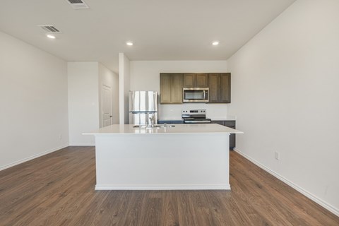 A kitchen with a white island and wooden floors.