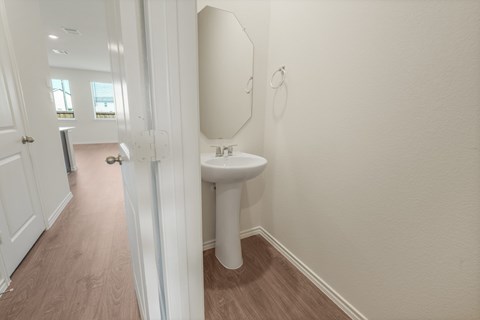 A white pedestal sink in a small bathroom.
