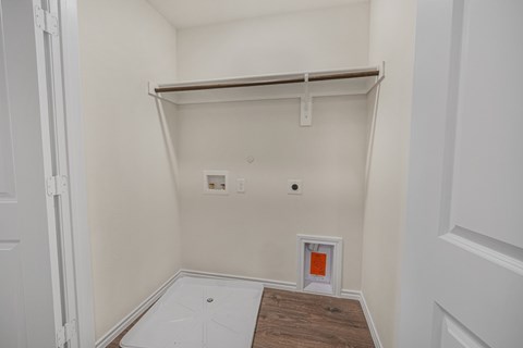 A small white closet with a shelf and a door.