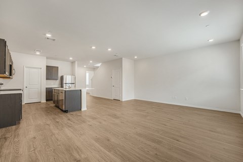 A spacious room with wooden flooring and white walls.