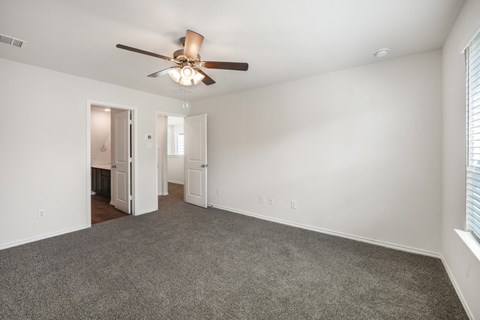 A room with a ceiling fan and carpeted floor.
