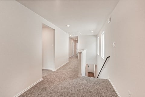 A long hallway with a carpeted floor and white walls.