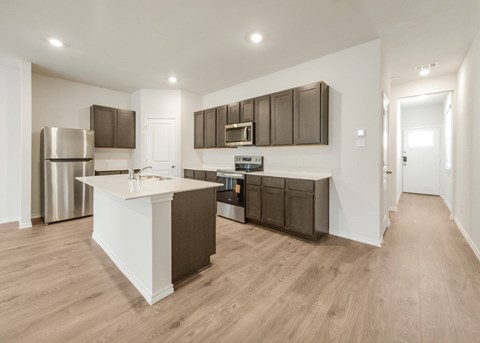 A modern kitchen with a white island and dark brown cabinets.