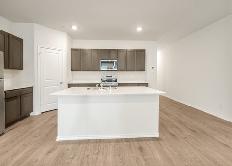 A kitchen with a white island and wooden floors.