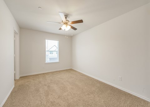 A room with a ceiling fan and carpeted floor.