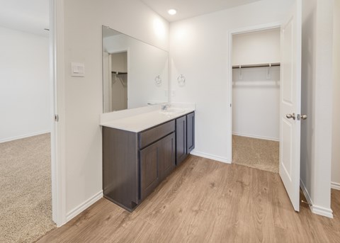 A large, empty room with a vanity and a doorway leading to another room.
