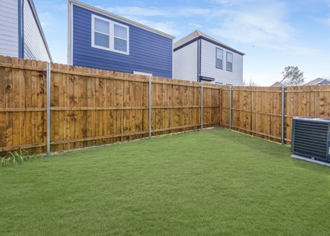 A backyard with a wooden fence and a green lawn.
