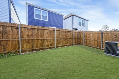 A backyard with a wooden fence and a green lawn.