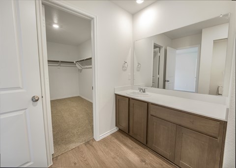 A bathroom with a white door, a sink, and a mirror.