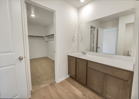 A bathroom with a white door, a sink, and a mirror.
