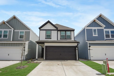 A house with a grey garage door is in front of two other houses.