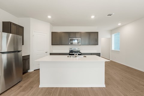 A modern kitchen with a stainless steel refrigerator and a white island.