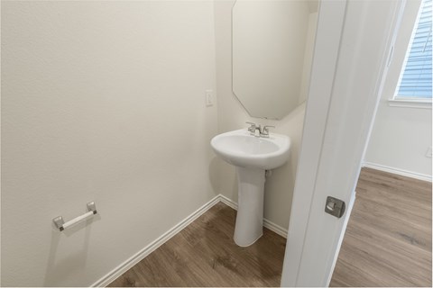 A white pedestal sink in a small bathroom.