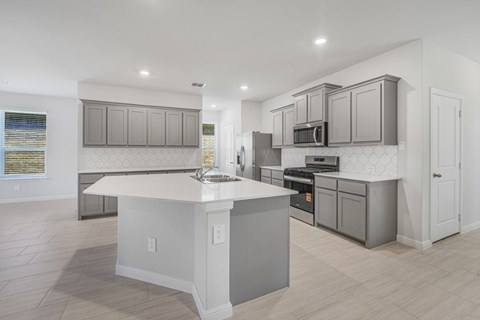 A modern kitchen with a white island and grey cabinets.