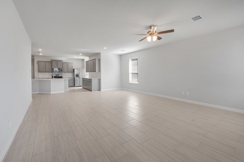 A spacious room with a ceiling fan and light wood flooring.