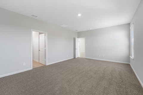 A large, empty room with carpeted flooring and white walls.