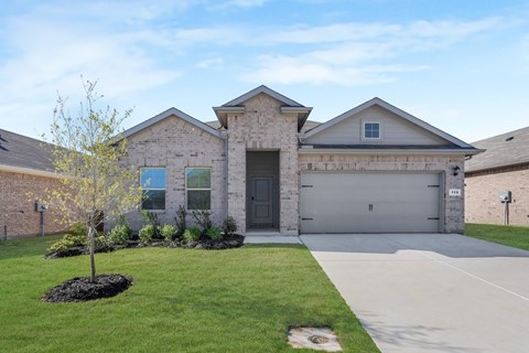 A house with a grey garage door and a tree in front.