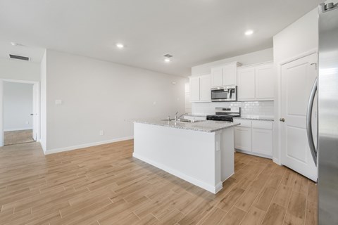 A kitchen with white cabinets and a wooden floor.