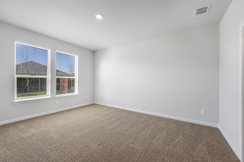 A room with carpeted floor and two windows.