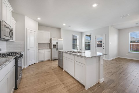 A spacious kitchen with white cabinets and a large island.