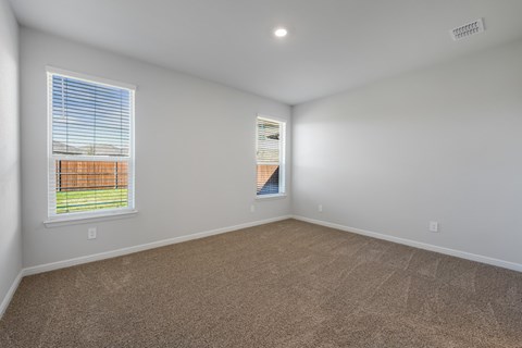 A room with a carpeted floor and a window showing a fence and a building outside.