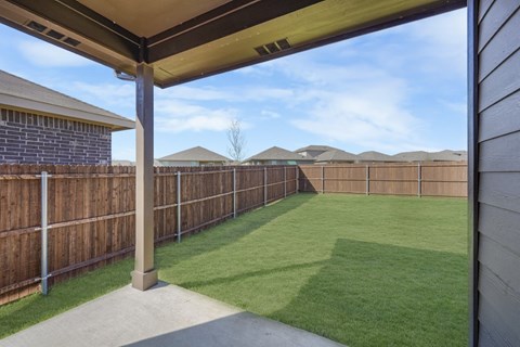 A backyard with a wooden fence and a covered patio area.