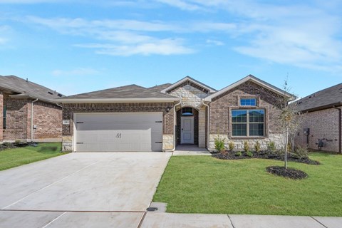 A house with a grey garage door and a brick wall.