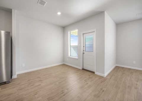 A spacious room with wooden flooring and a door leading to a balcony.