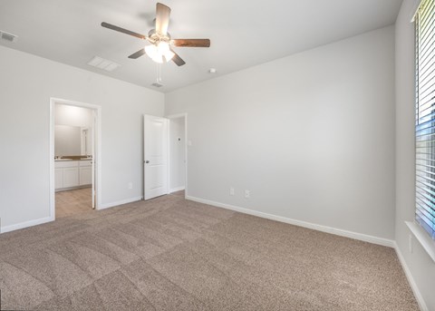 A room with a ceiling fan and carpeted floor.