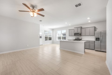 A spacious kitchen with a ceiling fan and lighting fixtures.