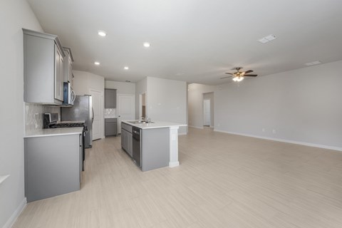 A spacious kitchen with a ceiling fan and lighting.