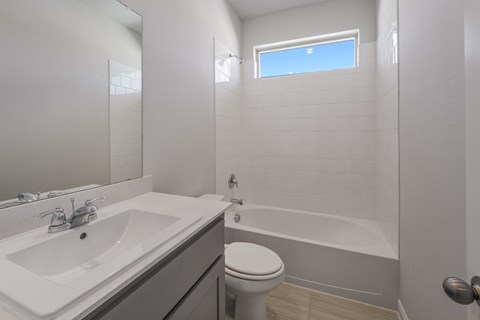 A white sink and toilet in a bathroom with a window.