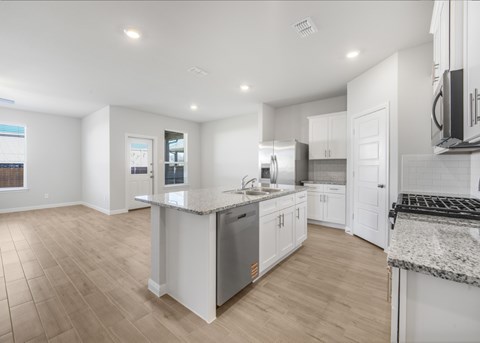 A spacious kitchen with white cabinets and a granite countertop.