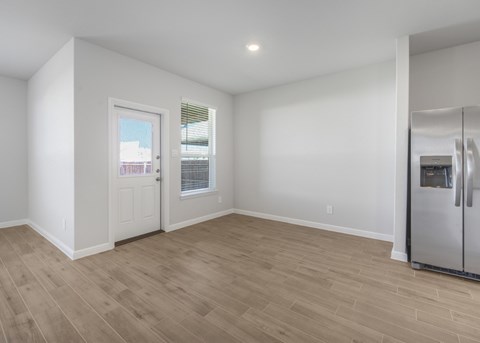 A spacious room with a door and a fridge.