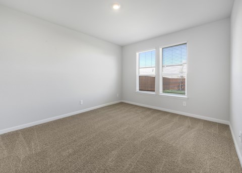 A room with a carpeted floor and two windows.