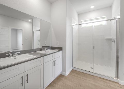 A bathroom with a walk-in shower and double sinks.