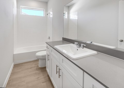 A white bathroom with a toilet, sink, and mirror.