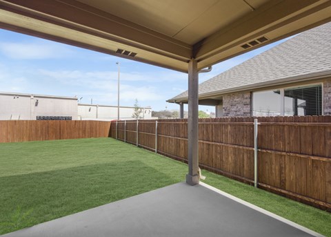 A patio with a wooden fence and a green lawn.