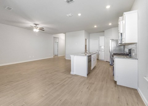 A spacious kitchen with white cabinets and a wooden floor.