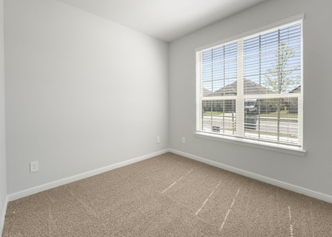 A room with a large window and carpeted floor.