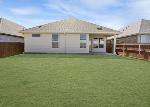 A backyard with a house and a green lawn.