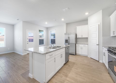 A kitchen with white cabinets and a marble countertop.